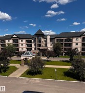 Multistory building exterior featuring a central turret, multiple balconies, a covered entry, and pitched roofs - 