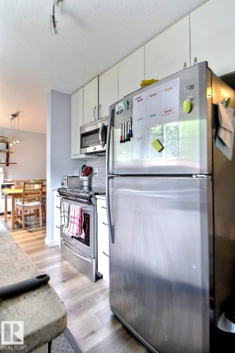 Kitchen featuring stainless steel appliances, light wood-finish flooring, white cabinetry, and a subway tile backsplash - 726 Saddleback Road, Edmonton, AB - Indoor Photo Showing Kitchen