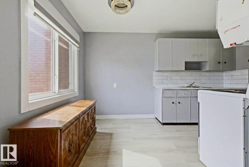Kitchen area featuring light wood-finish flooring, white cabinetry, and white subway tile backsplash - 15 10164 150 Street, Edmonton, AB 
