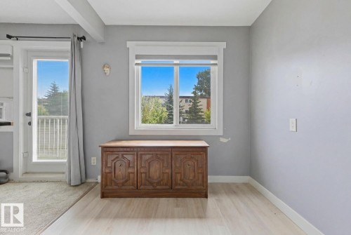 Bright interior space featuring a large window, a glass-paned door, light wood-finish flooring, and neutral wall tones - 15 10164 150 Street, Edmonton, AB 