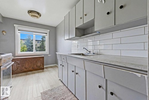 Kitchen featuring white subway tile backsplash and light-toned wood-finish flooring - 15 10164 150 Street, Edmonton, AB 