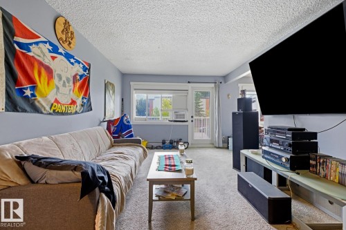 Living area featuring light gray walls, textured ceiling, and carpet flooring - 15 10164 150 Street, Edmonton, AB 