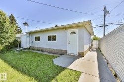 Light-colored stucco exterior with a durable base, featuring multiple windows and a front entry door with an arched glass insert - 