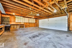 Spacious garage featuring a concrete floor, exposed wood beam ceiling, and a large white garage door - 