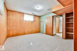 Spacious room featuring wood paneling, light-colored carpeting, and a drop ceiling - 
