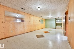Spacious room featuring wood paneling, an accent wall, tile flooring with decorative inserts, built-in shelving, and multiple ceiling-mounted light fixtures - 