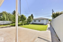 Rear exterior featuring a detached building with light blue siding, a dark shingle roof, and multiple windows - 