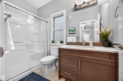 Bathroom featuring a brown vanity with a light-colored countertop, an integrated rectangular sink, and a large wall-mounted mirror - 