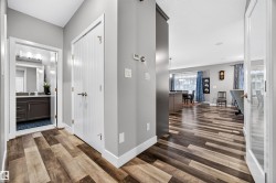 Hallway featuring wood-finish flooring, light gray walls, and white trim - 
