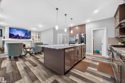 Kitchen featuring a central island with granite countertop, stainless steel appliances, and integrated dishwasher - 