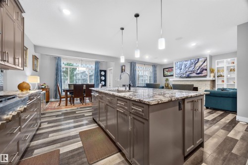 Kitchen island featuring a granite countertop, undermount sink, and pendant lighting - 1603 158 Street, Edmonton, AB 
