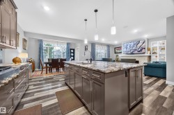Kitchen island featuring a granite countertop, undermount sink, and pendant lighting - 
