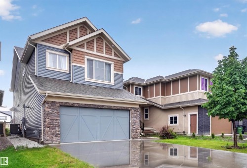 Contemporary exterior featuring blue siding, brown shingle accents, stone veneer, and a two-car garage - 1603 158 Street, Edmonton, AB 