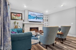 Living space featuring a stacked stone fireplace with an integrated linear electric insert, recessed lighting, and wood-finish flooring - 