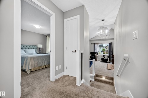 Carpeted hallway featuring light gray walls, white trim, and a white interior door - 1603 158 Street, Edmonton, AB 