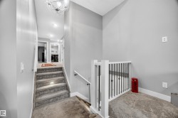 Carpeted staircase featuring inset step lighting and a white banister with black iron balusters - 