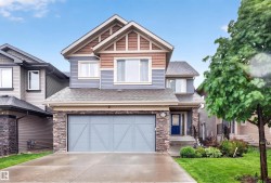 Two-story residence featuring a stone facade, blue siding, and textured wood-look gables - 