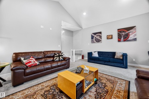 Spacious living area featuring vaulted ceilings, light gray wall paint, and gray carpet flooring - 1603 158 Street, Edmonton, AB 