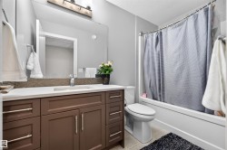 Contemporary bathroom featuring a spacious wood-finish vanity with ample storage, a white countertop, and an integrated sink - 