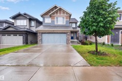 Contemporary two-story residence featuring a two-car garage with a decorative door, a blue front door, a stone facade accent, and a gabled roofline - 