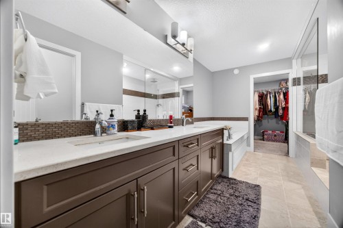Contemporary bathroom featuring a long double vanity with integrated sinks, light-toned countertops, and dark cabinetry - 1603 158 Street, Edmonton, AB 