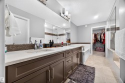 Contemporary bathroom featuring a long double vanity with integrated sinks, light-toned countertops, and dark cabinetry - 