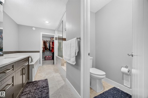 Bathroom featuring a spacious walk-in shower with a glass enclosure, a built-in bathtub, a double vanity with a light-toned countertop, and recessed lighting - 1603 158 Street, Edmonton, AB 