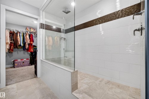 Walk-in shower with a glass enclosure, rain shower head, and an accent tile band - 1603 158 Street, Edmonton, AB 