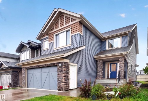 Contemporary two-story residence featuring a striking blue entry door, stone column accents, and horizontal siding - 1603 158 Street, Edmonton, AB 