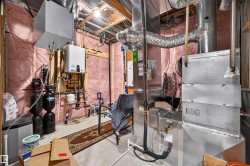 Basement utility area featuring exposed wood joists and pink insulation - 