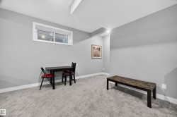 Spacious room featuring light gray wall paint, crisp white baseboards, and soft gray carpeting - 
