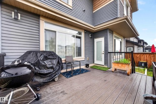Spacious outdoor deck featuring composite decking, a white exterior door, and a wooden planter box - 1603 158 Street, Edmonton, AB 