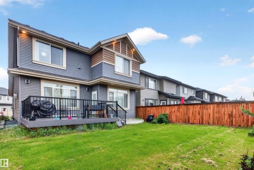 Expansive green lawn with a two-story residence featuring horizontal siding, a private deck with black railing, and a wood privacy fence - 1603 158 Street, Edmonton, AB 