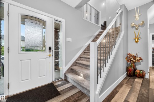 Entryway featuring a white paneled door with decorative glass, a sidelight, and wood-finish flooring - 1603 158 Street, Edmonton, AB 