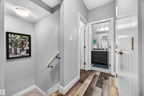 Hallway with wood-finish flooring, light grey wall paint, and white baseboards - 1603 158 Street, Edmonton, AB 