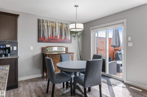 Dining area featuring wood-finish flooring, a contemporary pendant light fixture, and a sliding glass door to an exterior patio - 1651 Hammond Crescent, Edmonton, AB 