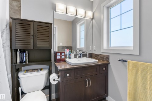 Bathroom featuring a dark wood-finish vanity with a surface-mount sink, an extended countertop, and a tiled backsplash - 1651 Hammond Crescent, Edmonton, AB 