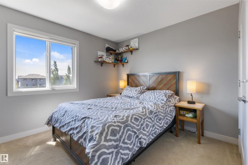 Bedroom featuring a light gray wall color, a white-framed window, and neutral-toned carpeting - 1651 Hammond Crescent, Edmonton, AB 