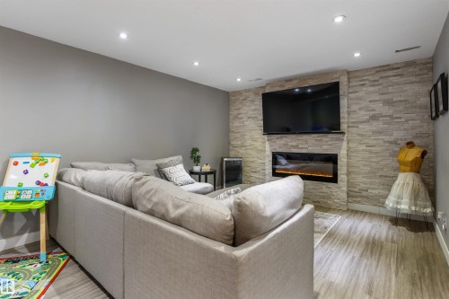 Living area with light grey walls, recessed lighting, wood-finish flooring, and a stone-clad feature wall - 1651 Hammond Crescent, Edmonton, AB 