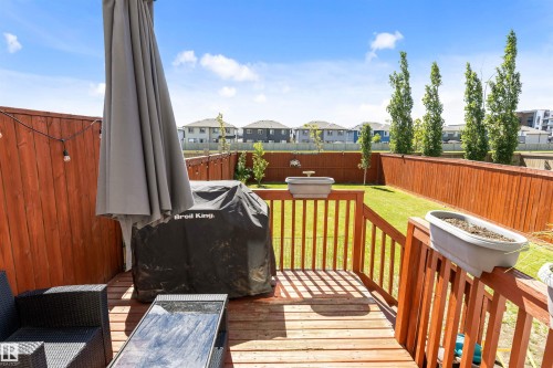 Private backyard featuring a wooden deck, slatted wood fencing, and a manicured lawn - 1651 Hammond Crescent, Edmonton, AB 