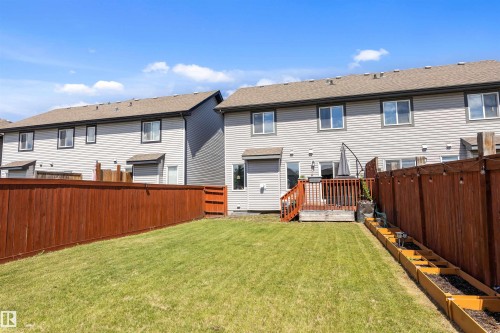 Private backyard featuring a wooden deck with railing, a grass lawn, and a stained wood fence - 1651 Hammond Crescent, Edmonton, AB 