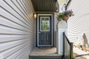 Front entry featuring a dark gray door with windowpanes, wood steps, and a black metal handrail - 1651 Hammond Crescent, Edmonton, AB 