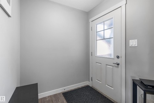 Entryway featuring a white paneled door with a multi-pane frosted glass insert, brushed nickel hardware, and wood-finish flooring - 1651 Hammond Crescent, Edmonton, AB 