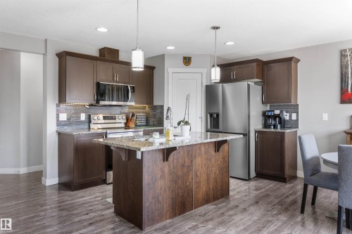 Kitchen featuring a central island with a granite countertop, wood-finish flooring, stainless steel appliances, and recessed lighting - 1651 Hammond Crescent, Edmonton, AB 