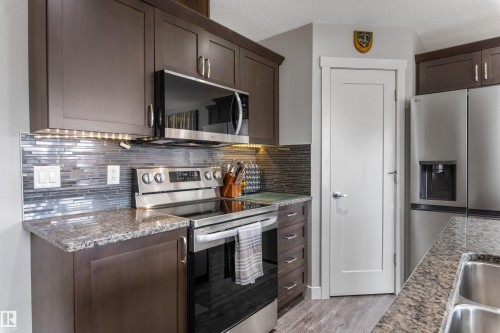 Kitchen featuring dark wood-finish cabinetry, granite countertops, and a full stainless steel appliance package - 1651 Hammond Crescent, Edmonton, AB 