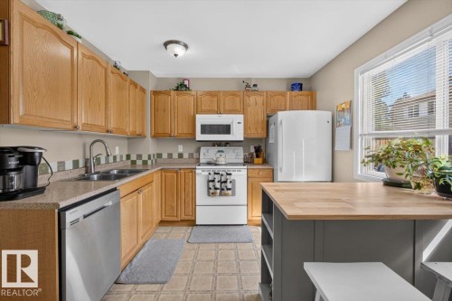 Kitchen featuring oak cabinetry and a built-in stainless steel dishwasher - 27 Walden Park, St. Albert, AB 
