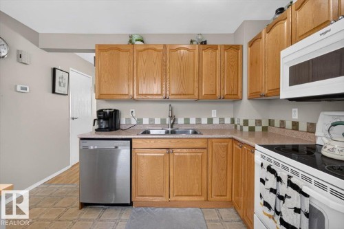 Kitchen featuring wood cabinetry, laminate countertops, stainless steel sink, tile backsplash, and stainless steel dishwasher - 27 Walden Park, St. Albert, AB 