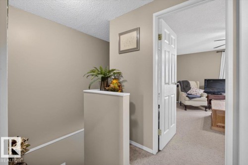 Hallway with neutral painted walls and white trim - 27 Walden Park, St. Albert, AB 