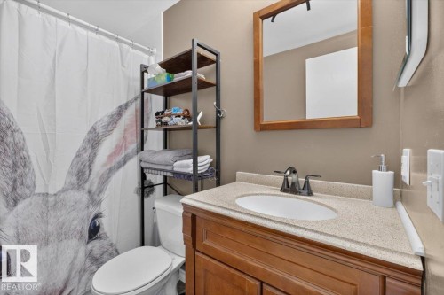 Bathroom featuring a wood vanity with an integrated sink, a light-colored countertop, and a wood-framed mirror - 27 Walden Park, St. Albert, AB 