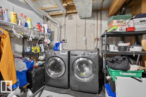 Dedicated laundry area featuring a concrete wall finish, exposed ceiling joists, and utility shelving - 27 Walden Park, St. Albert, AB 
